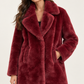 Cappotto donna HAVEONE effetto pelliccia bordeaux su modella, dettaglio – immagine elaborata con IA