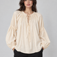 Blusa panna con scollo arricciato e laccetti, lunghe maniche morbide – fronte su modella