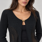 Cardigan nero cropped con pannelli traforati e piccola chiusura dorata – dettaglio su modella