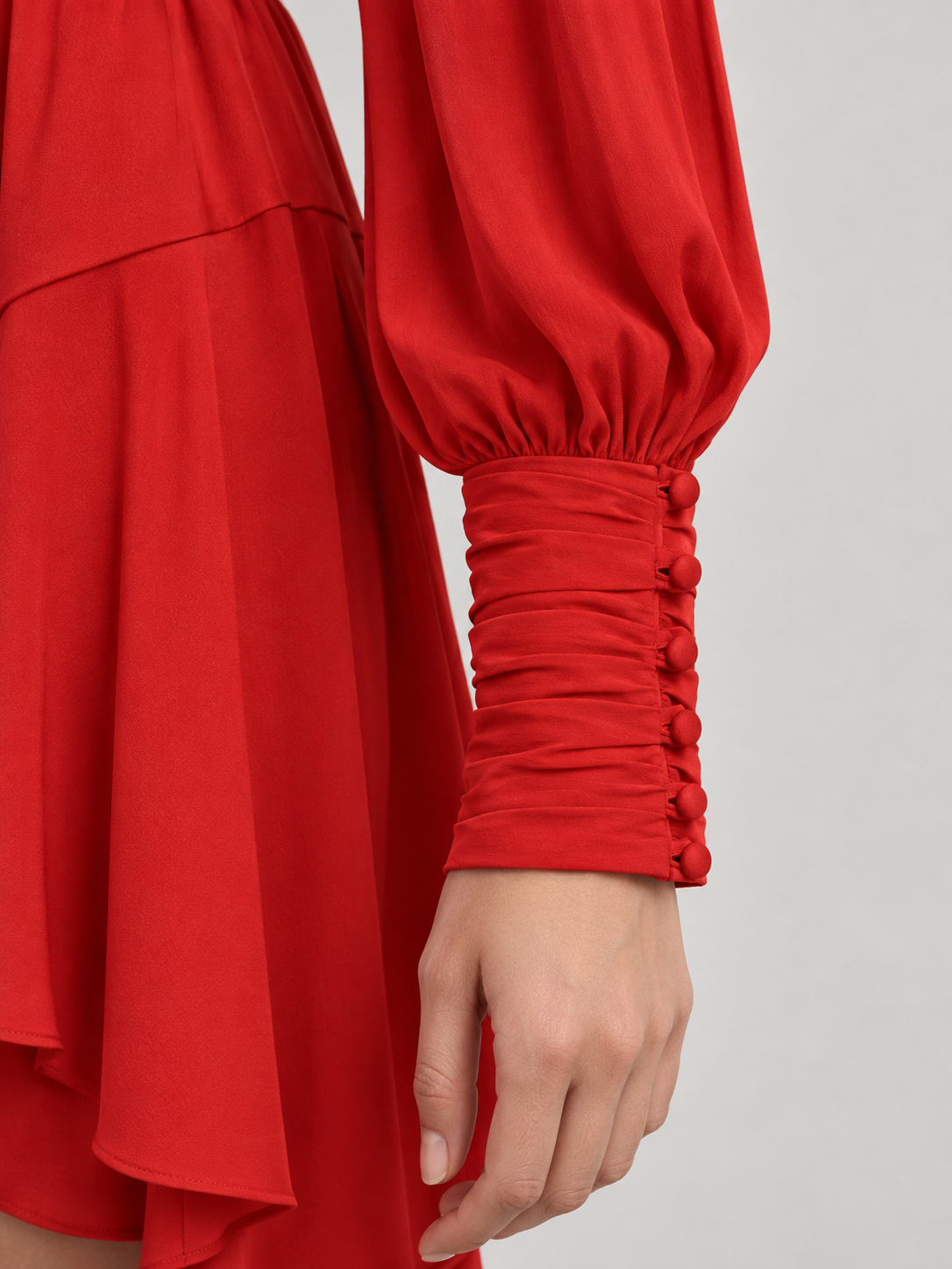 Abito Pinko rosso con scollo incrociato e polsini arricciati — dettaglio su modella (immagine generata con AI)